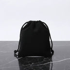 Black drawstring pouch for jewelry or gift packaging on marble surface.
