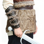 viking leather bracers for cosplay displayed on a warrior's arm with faux fur accents and a sword.